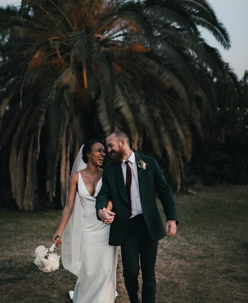 a newly married couple walking through a field