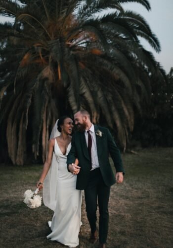 a newly married couple walking through a field